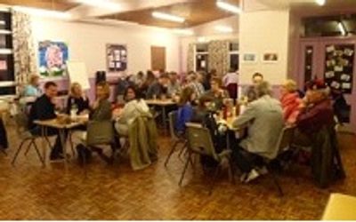 A social gathering of people seated around tables indoors.