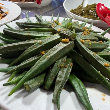 Steamed green okra pods topped with minced garlic and sauce