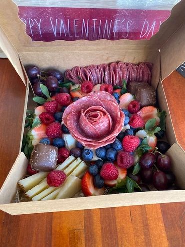 Valentine's Day charcuterie box with fruits, cheese, and salami rose.