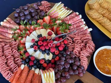 A vibrant charcuterie board with meats, cheeses, grapes, berries, strawberries, and crackers.