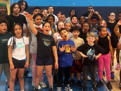 A diverse group of excited children posing in a gymnasium.