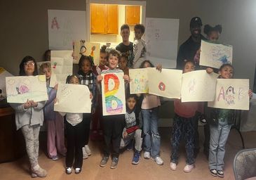 Group of children proudly displaying their colorful drawings indoors.