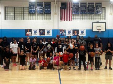 A diverse group of young basketball players and coaches pose in a gymnasium.
