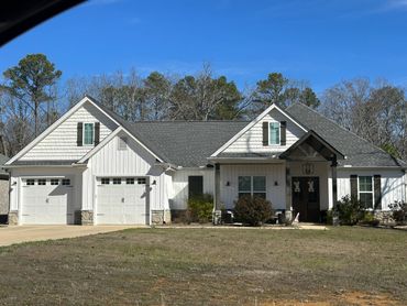 Modern white house with gray roof and double garage under clear blue sky.