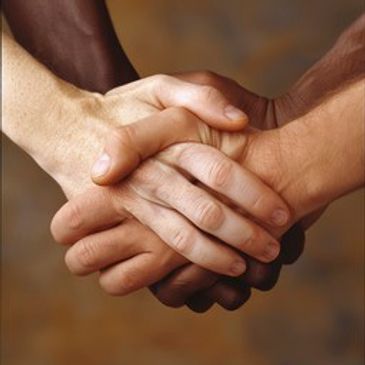 Two hands of different skin tones clasped together.