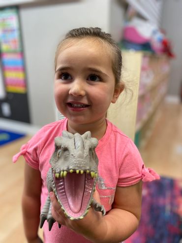 A girl holding a dinosaur toy