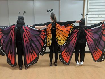 Three people wearing butterfly costumes