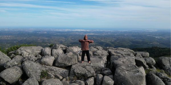 Person standing on large rocks overlooking scenic mountains.