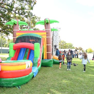 Children playing near an inflatable slide at a park.