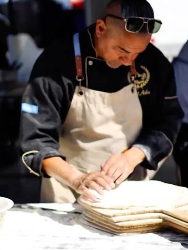 Chef preparing dough in an apron.