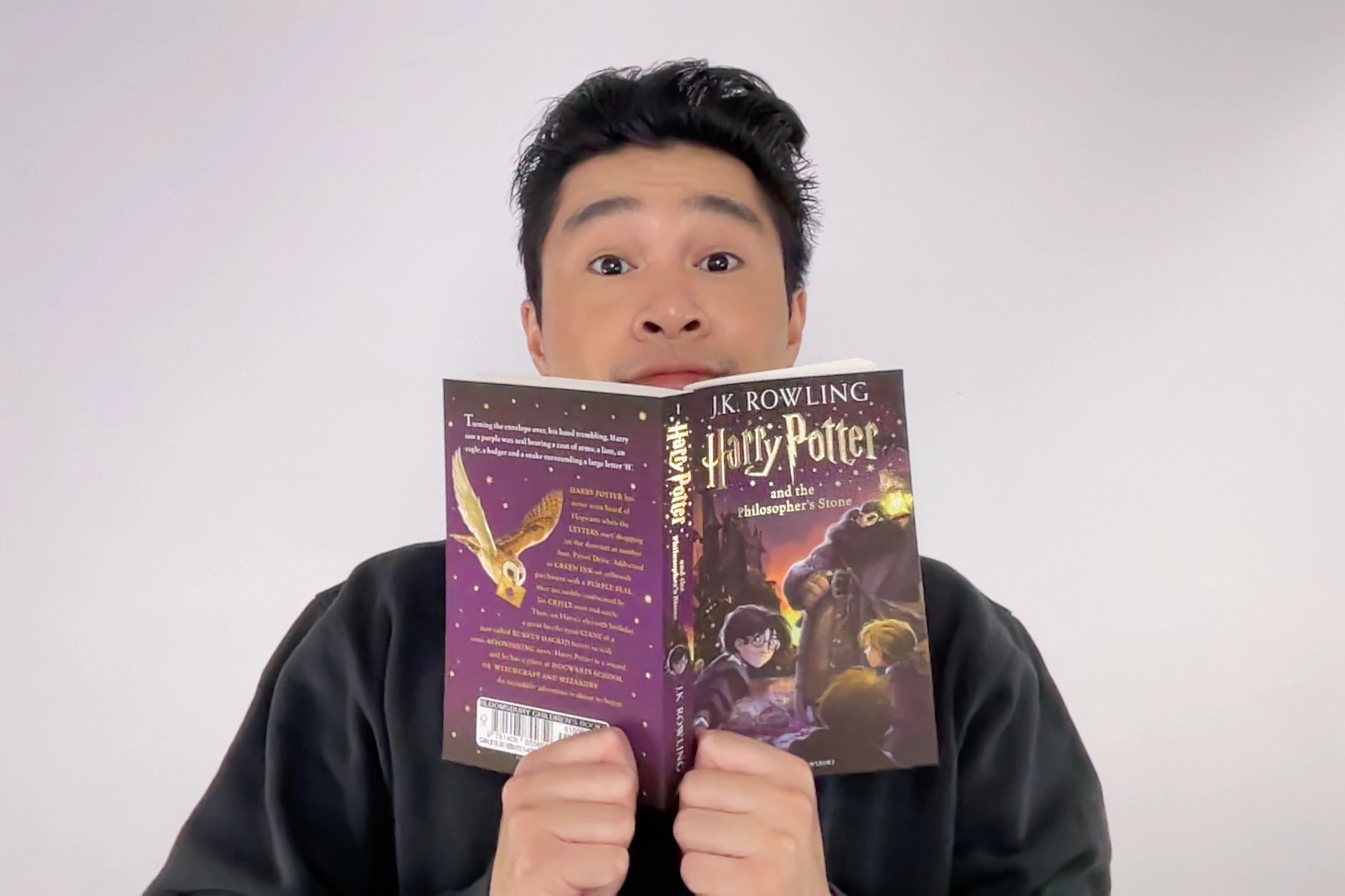 Man reading "Harry Potter and the Philosopher's Stone" with a surprised expression.
