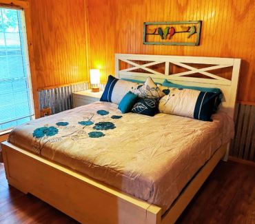 Cozy bedroom with wooden walls and floral bedding in teal and beige.