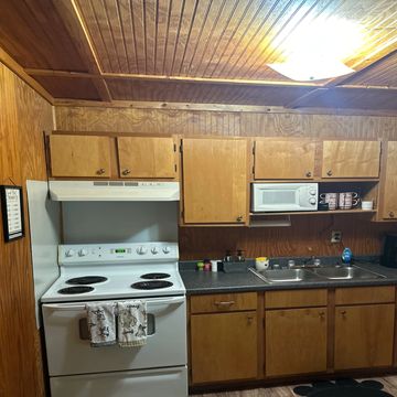 Cozy kitchen with wooden cabinets, white appliances, and a paw-shaped rug.