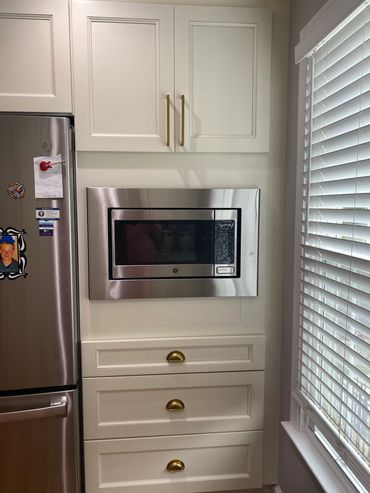 Built-in microwave oven in white kitchen cabinetry.