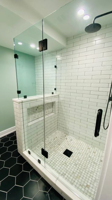Modern glass shower with white subway tiles and hexagonal floor tiles.