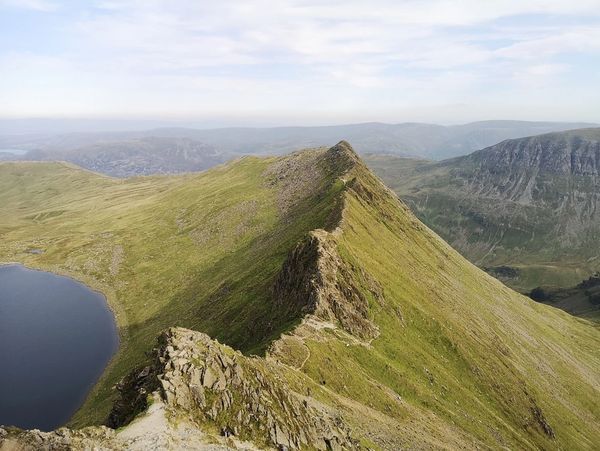 The Striding Edge mountain peak near a lake with a blue sky in the background