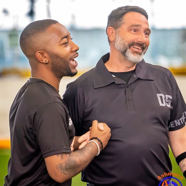 Two men smiling and holding hands, enjoying a moment together.