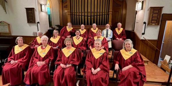 Choir group in red and yellow robes inside a church.
