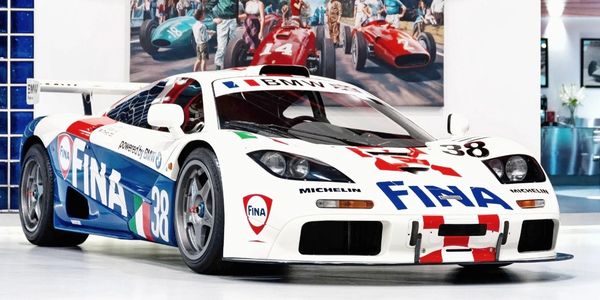 White and blue FINA race car with number 38 in a showroom.