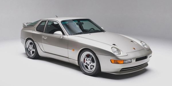 Silver Porsche 928 sports car in a studio setting.