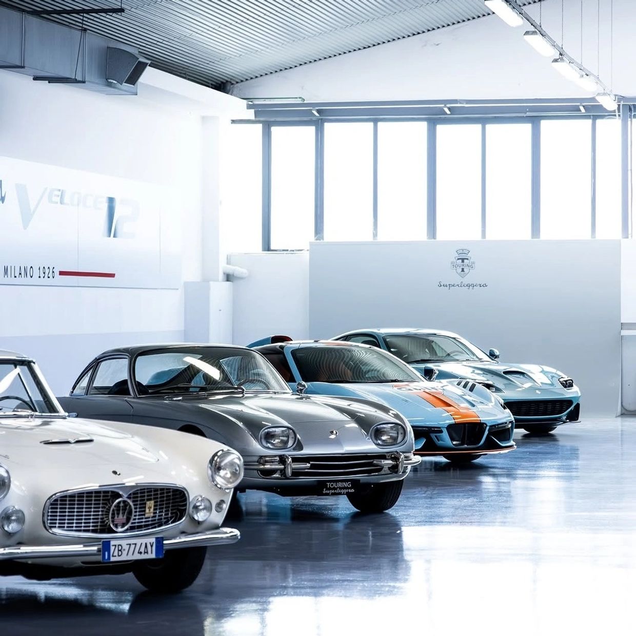 A lineup of vintage and modern sports cars in a showroom.