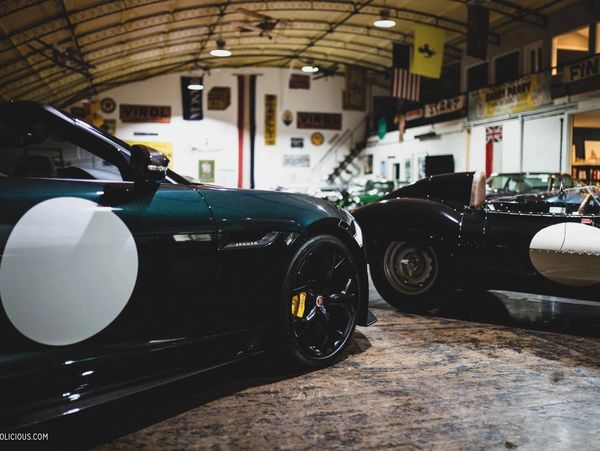 Two vintage race cars parked indoors in a rustic garage.