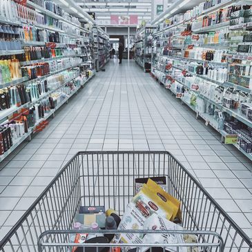 View from a shopping cart in a well-stocked supermarket aisle.