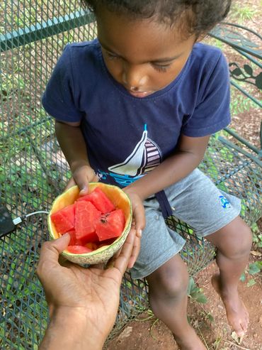 Child holding cantaloupe bowl with watermelon pieces.