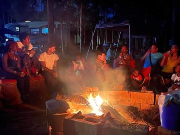 Group enjoying a nighttime campfire in the woods.