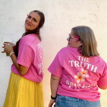 Two women in pink shirts smiling.