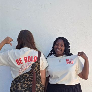 Two women wearing "Be Bold" t-shirts.