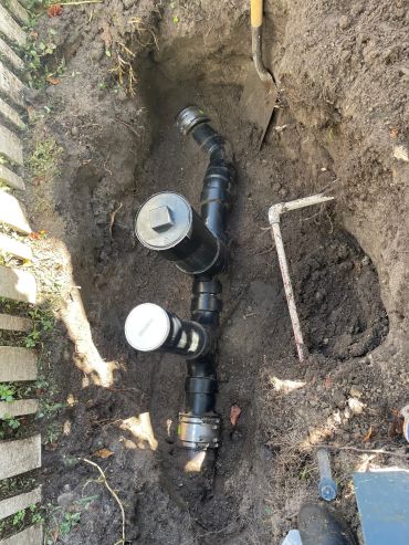 Buried underground plumbing pipes with shovel and metal tool.