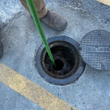 Person using a green tool in a manhole.