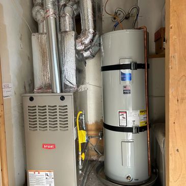A residential furnace and water heater installed in a utility closet.