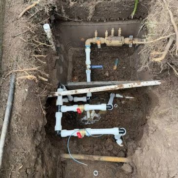 Excavated ground box with visible irrigation and water pipes.