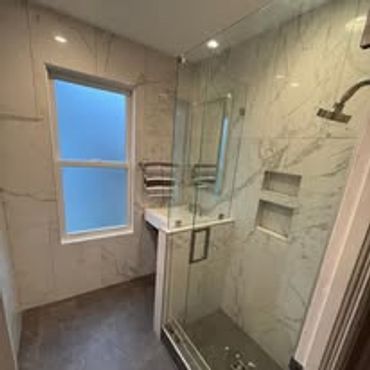 Modern bathroom with glass shower and marble walls.