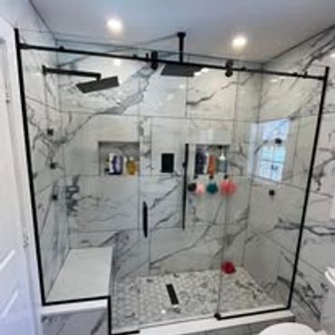 Modern marble bathroom with glass shower enclosure and built-in bench.