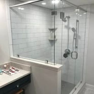 Modern glass shower enclosure with white subway tiles and chrome fixtures.