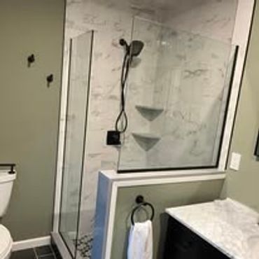 Modern bathroom with glass shower and marble walls.