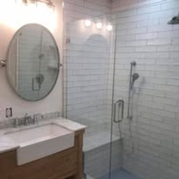 Modern bathroom with glass shower and oval mirror.
