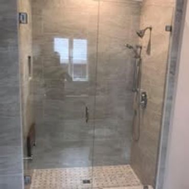 Modern glass-enclosed bathroom shower with beige tiles.