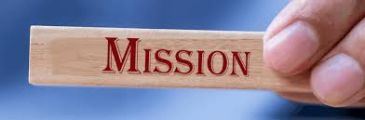 Hand holding a wooden block with the word 'MISSION'.