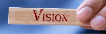 Hand holding a wooden block with the word 'VISION'.