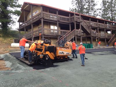 Paving Crew installing asphalt with a paving machine on a newly subgraded parking lot.