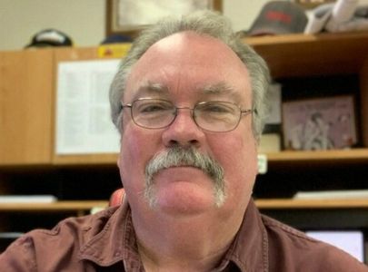 Steve Simpson. A man with gray hair and mustache wearing glasses and a reddish brown collared shirt