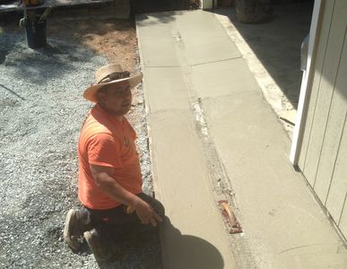 Crew Member kneeling in front of the concrete gutter he created to fix drainage in front of garage