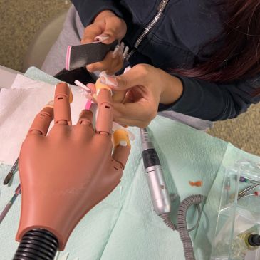 Person practicing nail art on a mannequin hand.