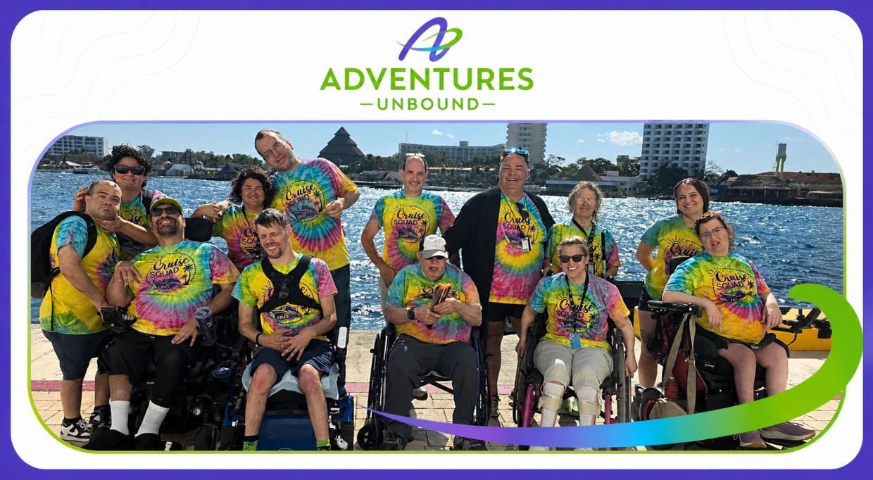 Group of people in colorful tie-dye shirts posing by the water with 'Adventures Unbound' logo.