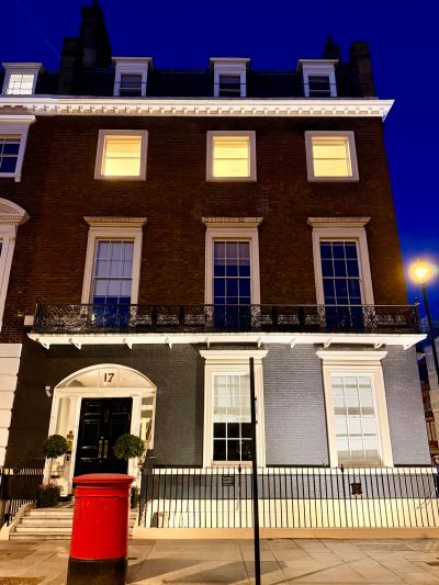 A three-story house with lit windows at night and a red mailbox in front.