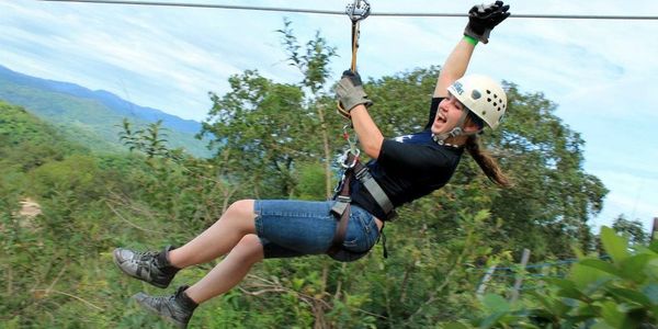Young woman enjoying a zipline ride over a lush forest.